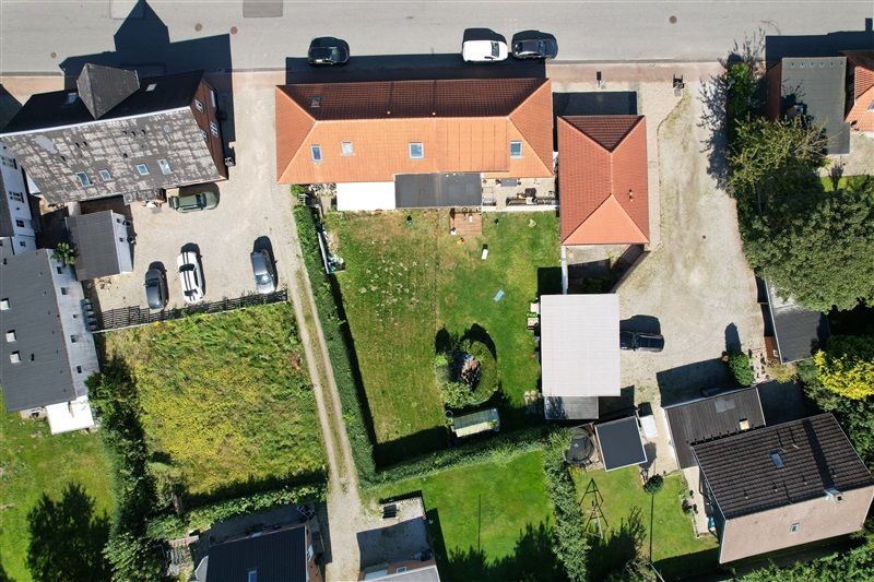 Forskellige huse med parkeringspladser og haver i Taulov, med en større grøn græsplæne og et hvidt hus i baggrunden