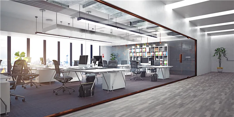 Glasvæggede kontorrum med skriveborde og stole. Der er to bøjle, hvor der er hængt to monitorer og en computer. En plante i