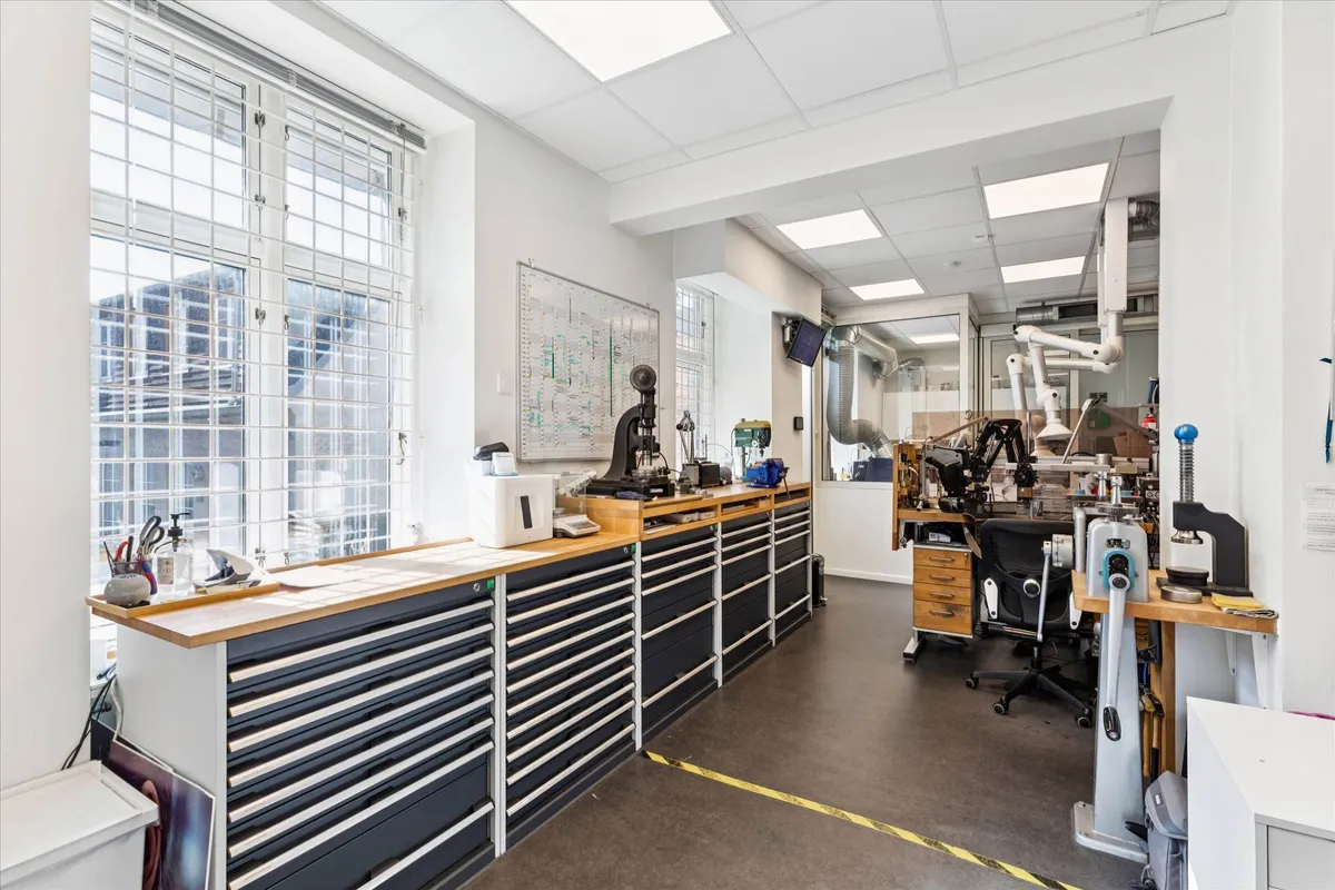 Kontor med en skrivebord, flere skrivebordslys og diverse maskiner samt en skrivebordspresse