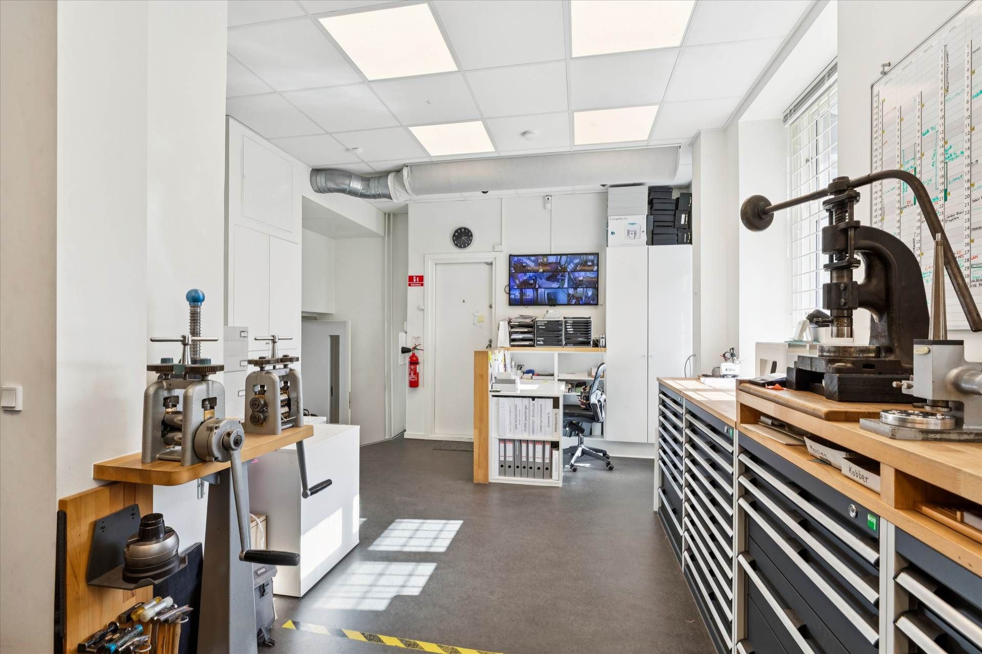 Et værksted med en skrallepresse og en række maskiner samt et stolpebord med flere værktøjer