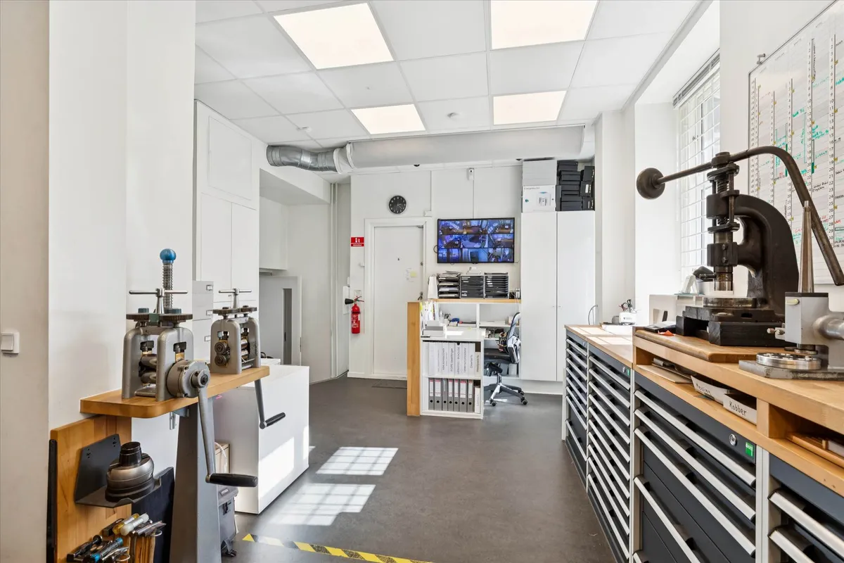 Et værksted med en skrallepresse og en række maskiner samt et stolpebord med flere værktøjer