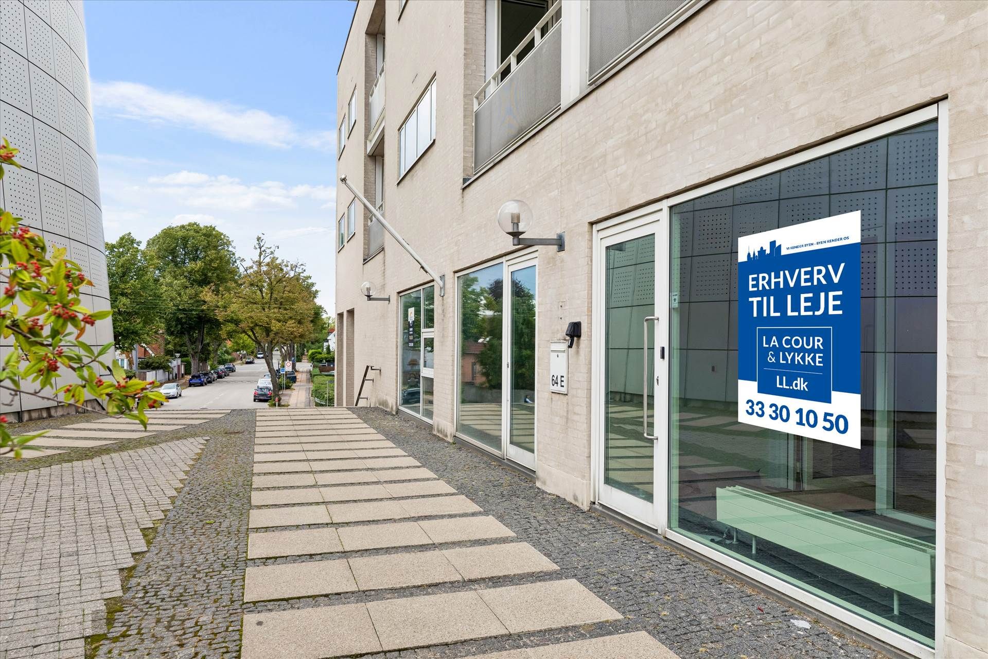Kontor med glasdøre og en skilt med teksten Erhverv til Leje placeret på Strandvejen i Hellerup