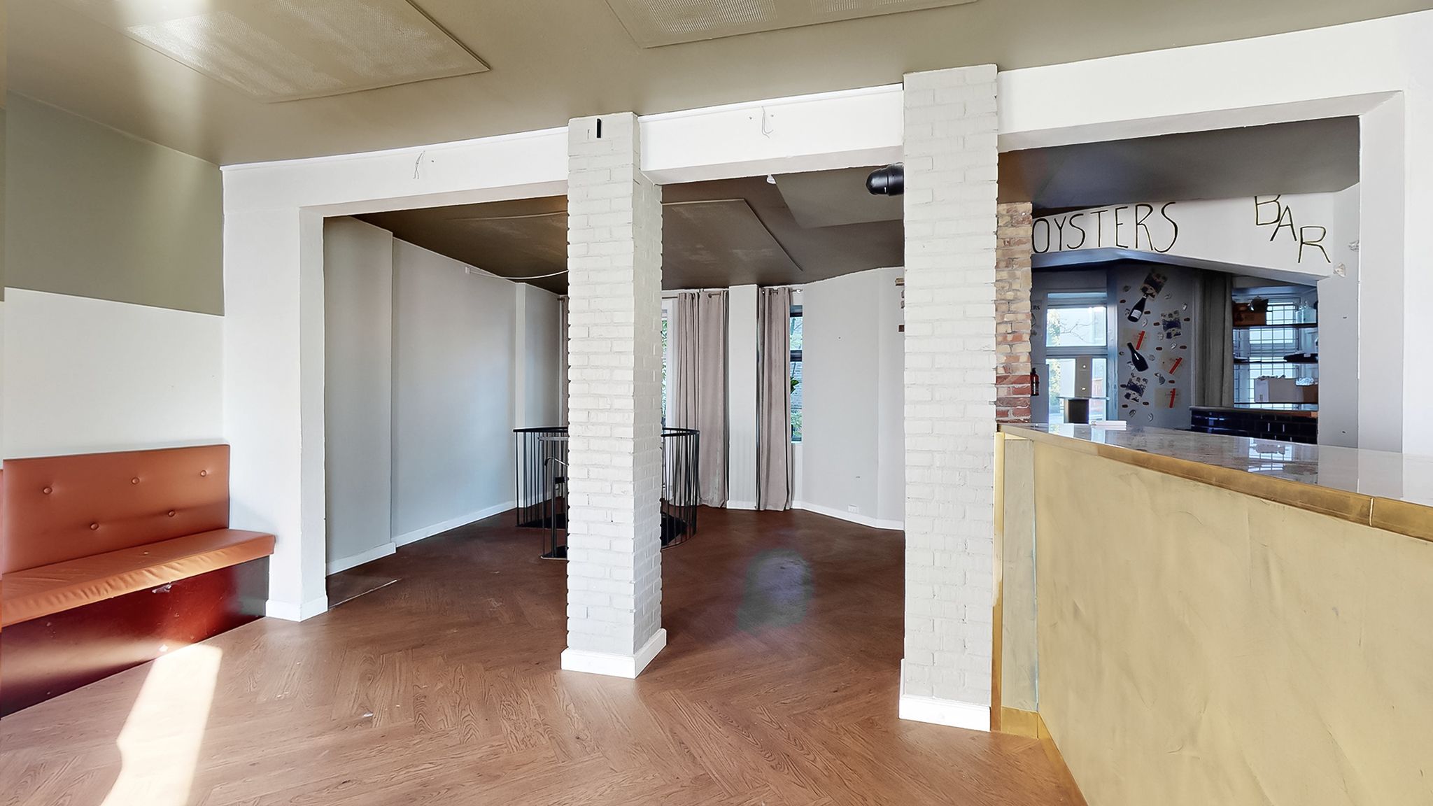 Inde i lokale med højt loft og masser af lys, gulvbelægning og loft i træ, høj kælder med lyse stenmure og udgang til