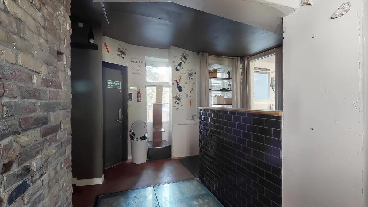 En tømrer tilrettelagt garderobe med åbne døre og en tøjstativ med tøj. Køkken med urtavle og vinflasker samt en ovn. Sorte