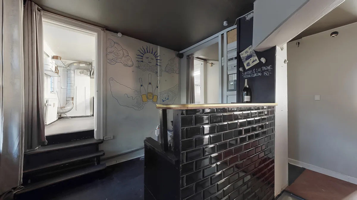 Sort og hvid interiør med gult brædt og sol på væggen og en stol med glasflaske udenfor