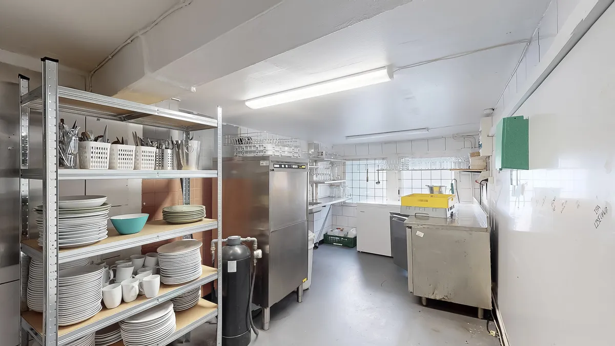 En ren og velorganiseret kommerciel køkken med rustfrit stål apparater, opbevaringsskabe og lyse hvide vægge