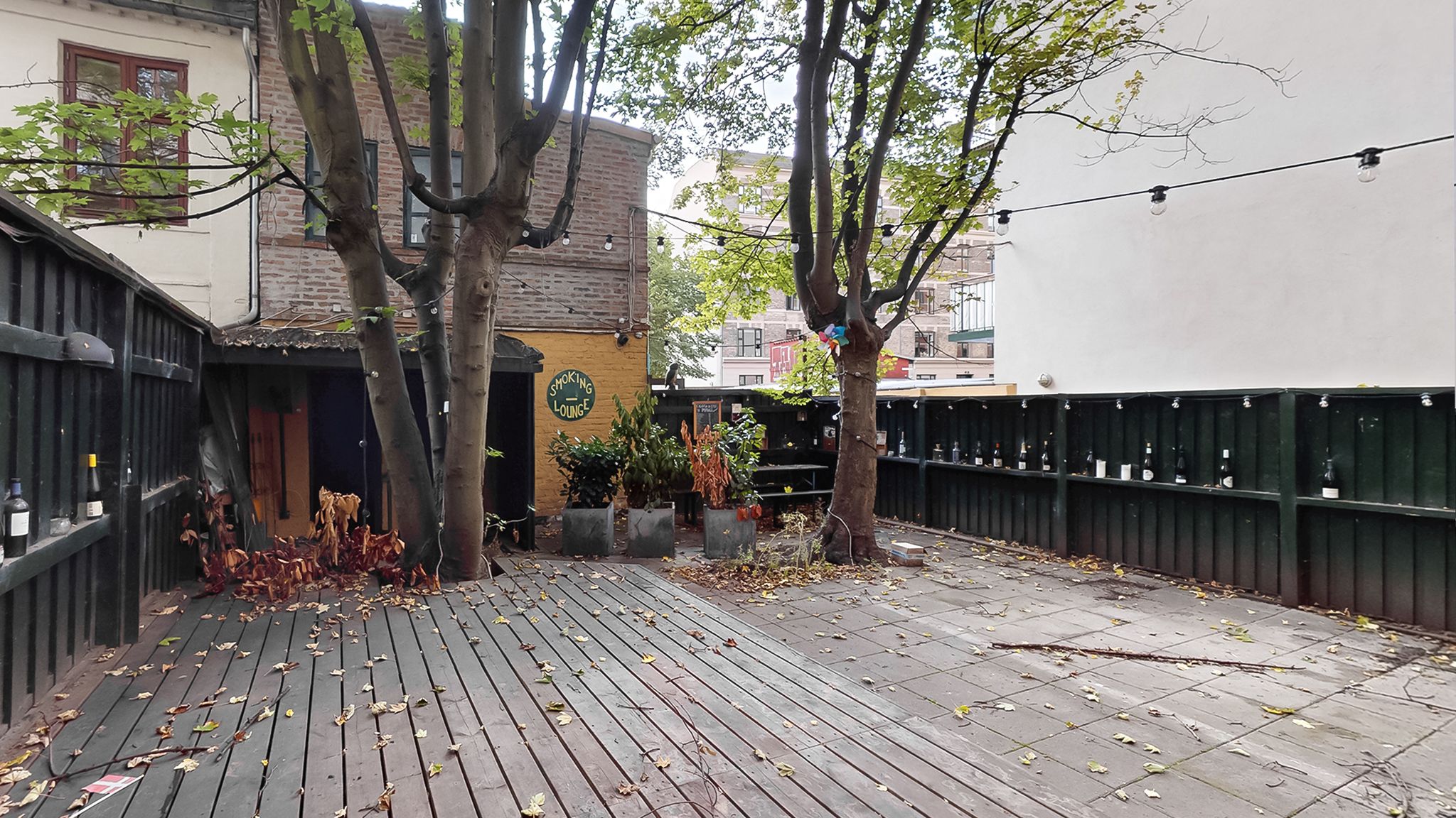 En have med træer og vinflasker samt et skilt, der siger smoking lounge
