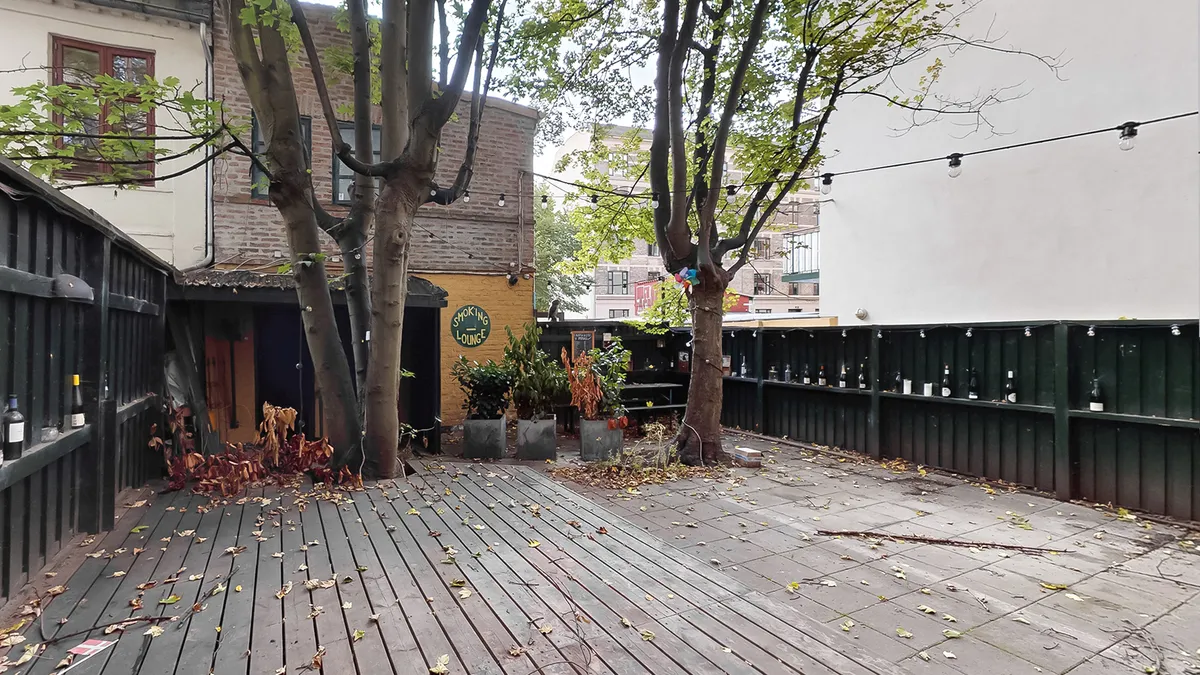 En have med træer og vinflasker samt et skilt, der siger smoking lounge