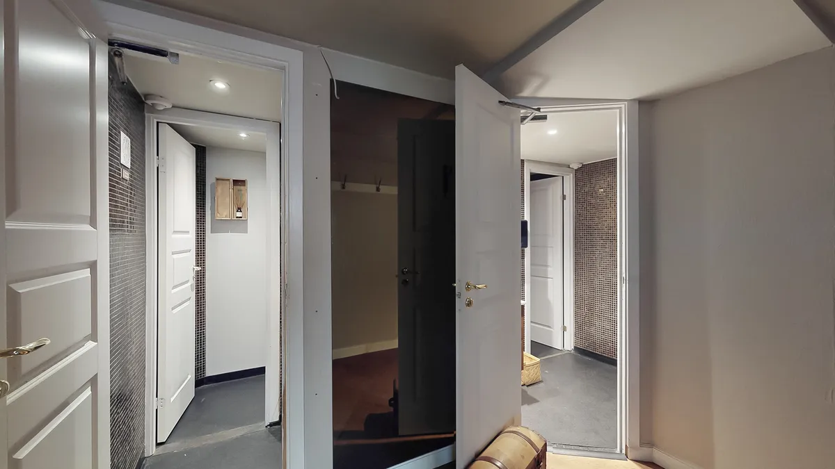 Hjørne af et kælderrum med åbne døre og lys præsenterer en lyse og rummelige kælder med moderne indretning og funktionelle