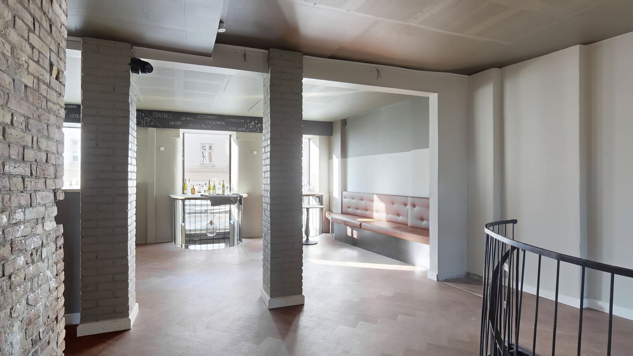 Indvendigt af en indkøbscenter med en lyse beige væg og en stor rødmalet bjælke, hvor der er et bord og et skrivebord med