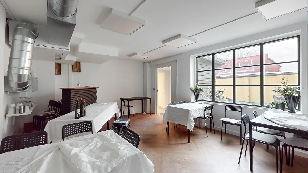 Indvendigt er der en stor stue med borde og stole, hvor bordene er dækket med hvide tæpper og vinflasker på bordene