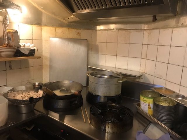 En køkken med to stålgryder og to kogeapparater samt en række ingredienser, der er placeret på et bord