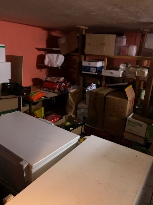 Lager med køleskab og flere kartoner, der er fyldt med forskellige produkter og varer