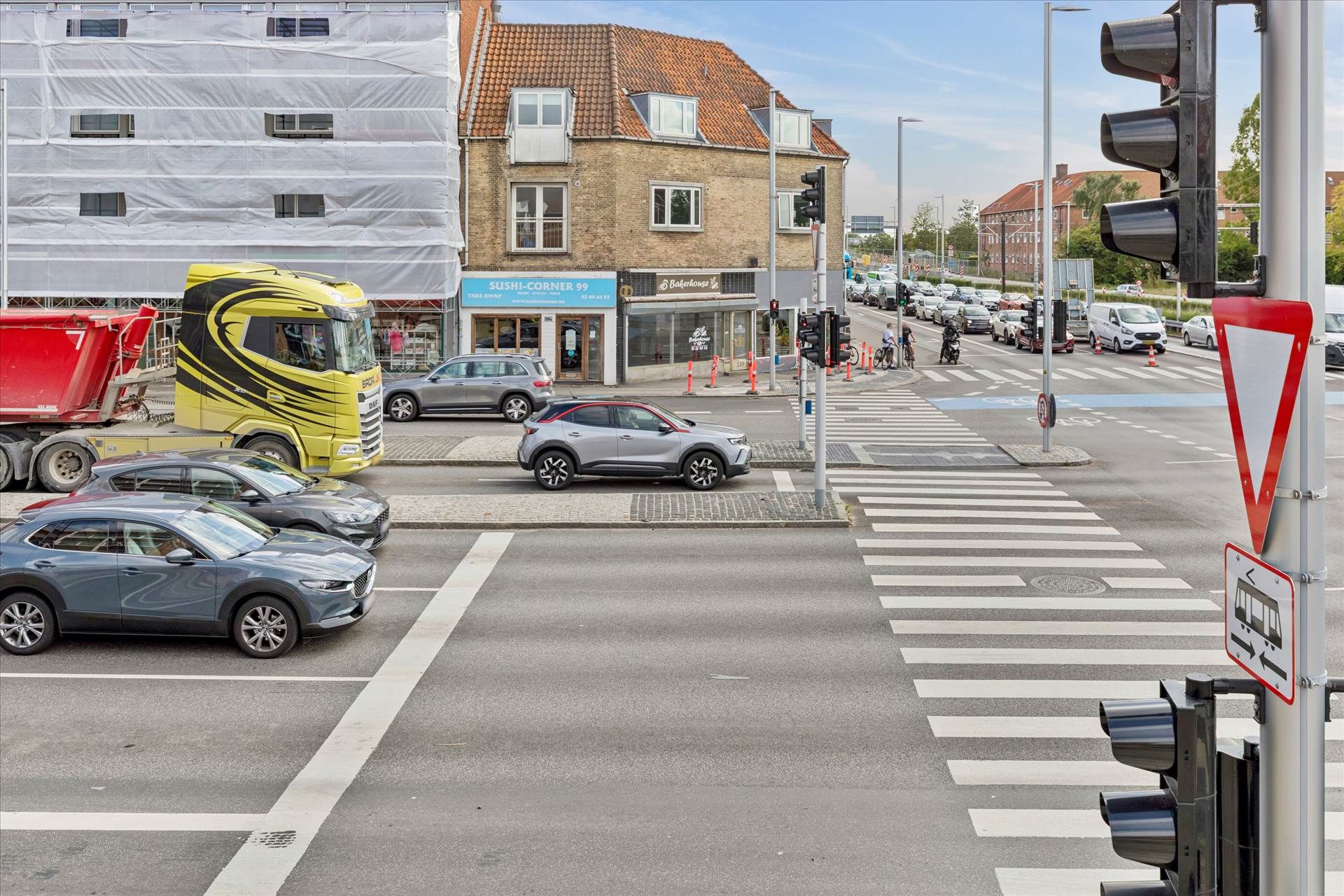 Et trafikfoto af en trafiksnart med en stor bus, biler og en cykel og et kryds med en krydslygte