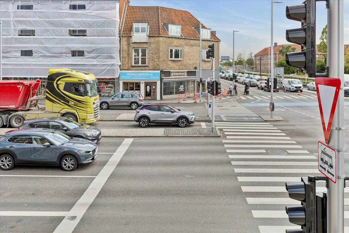 Et trafikfoto af en trafiksnart med en stor bus, biler og en cykel og et kryds med en krydslygte