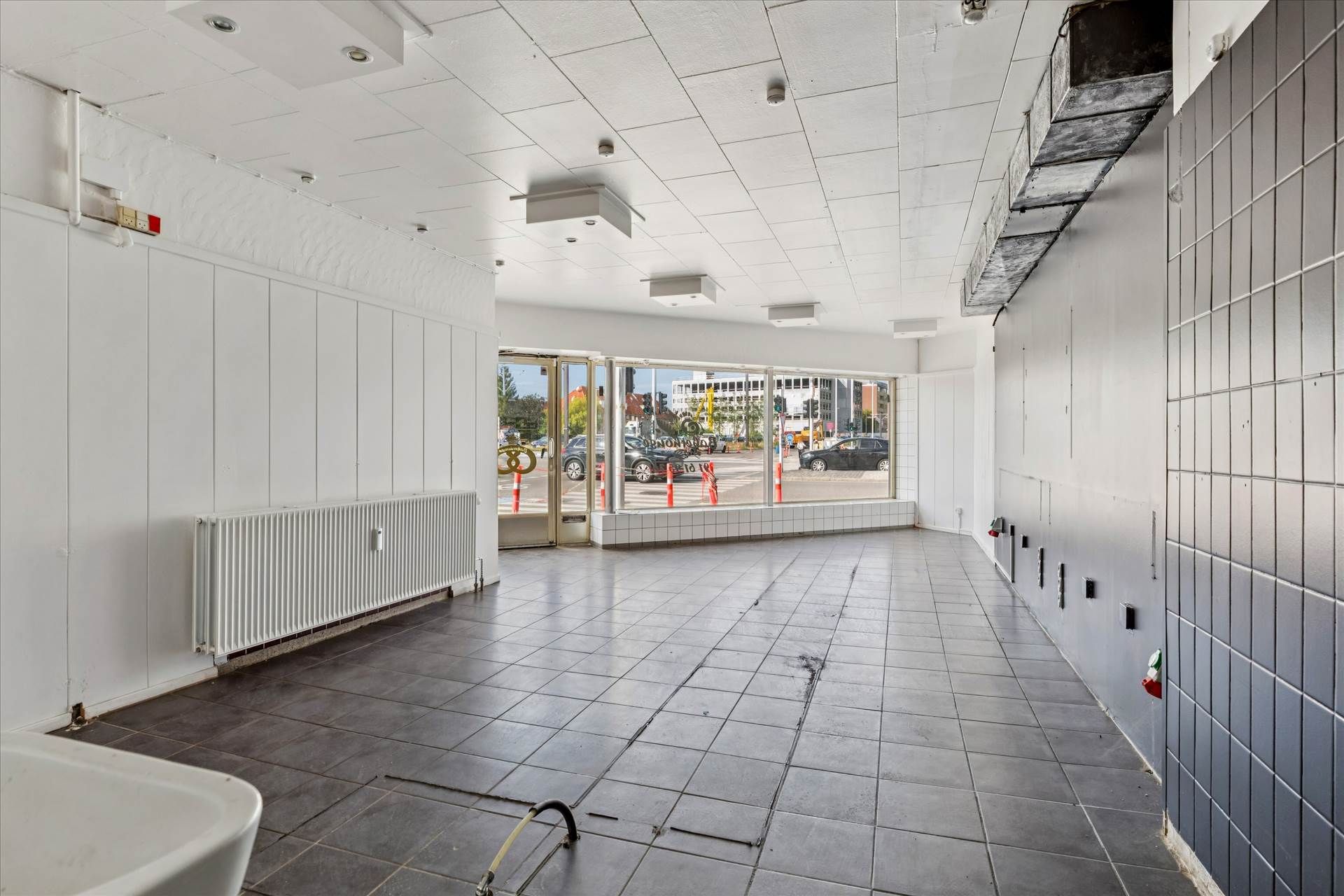 En tom og nyrenoveret forretningslokal i en højtravet bygning med højt til loftet og glasdøre