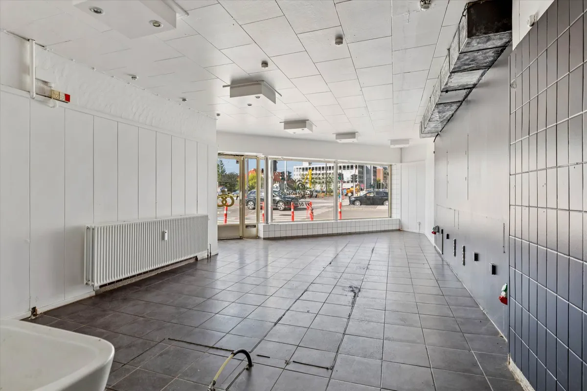 En tom og nyrenoveret forretningslokal i en højtravet bygning med højt til loftet og glasdøre