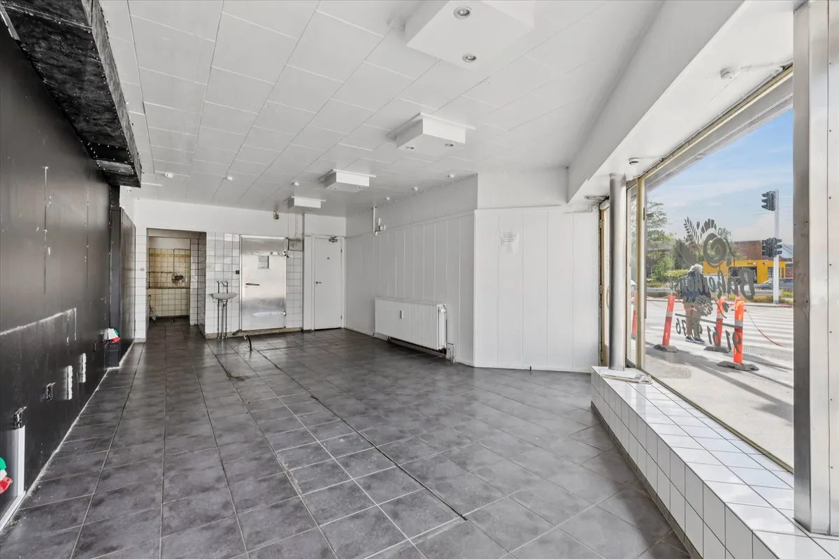 En lejlighed med et stort vindue og et indre med en radiator, en dør og en åbning til et badeværelse