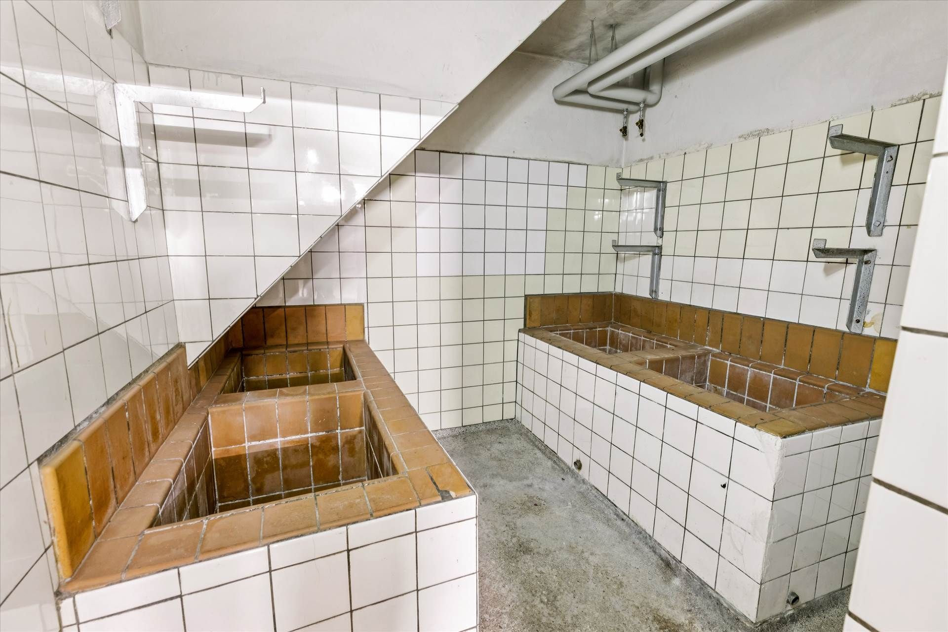 To bassiner med samme design er installeret på hver side af en vaskeskab. Der er tre lyse, metalhylder, der er monteret på