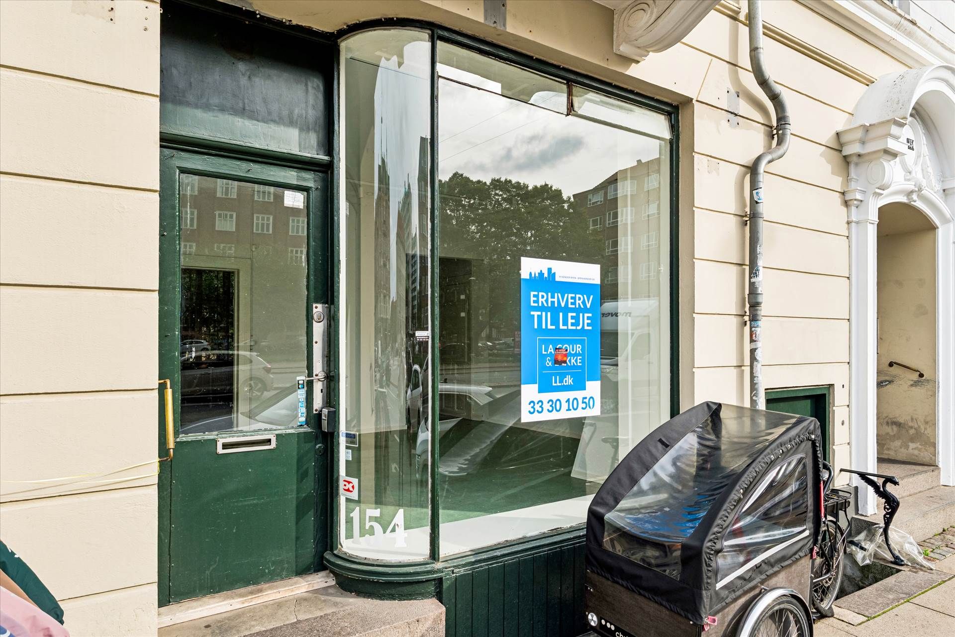 En butik med glasruder og en reklame for Erhverv til Leje. En kørestol står foran døren.