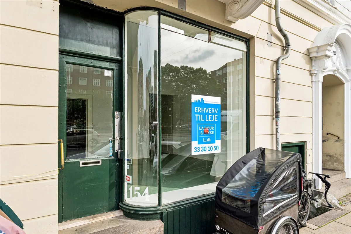 En butik med glasruder og en reklame for Erhverv til Leje. En kørestol står foran døren.