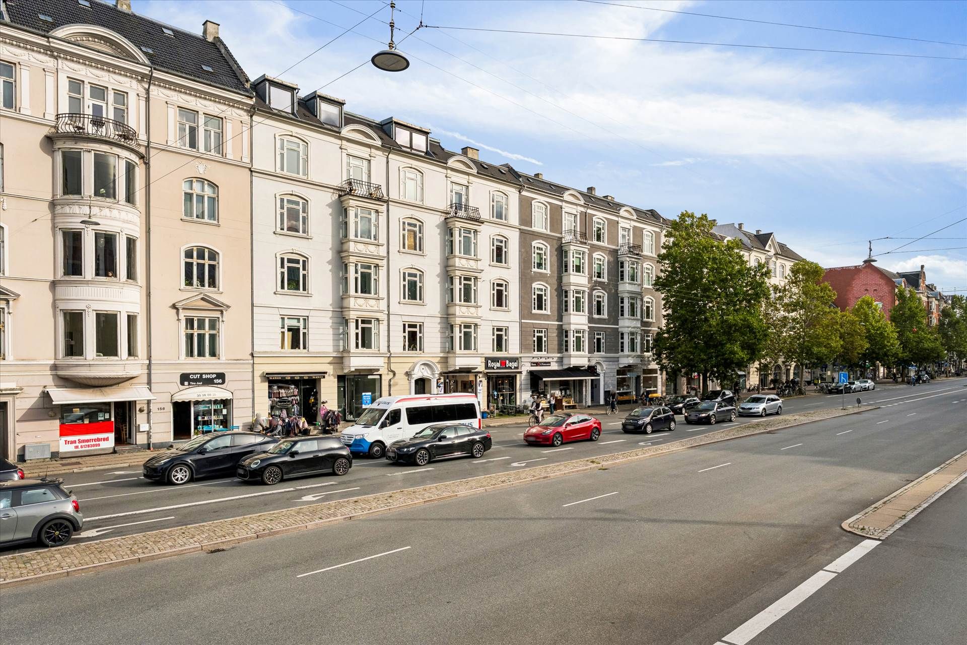 En bilparkeret vej med bygninger, der ligger langs gaden, en bilvask og flere parkerede biler.