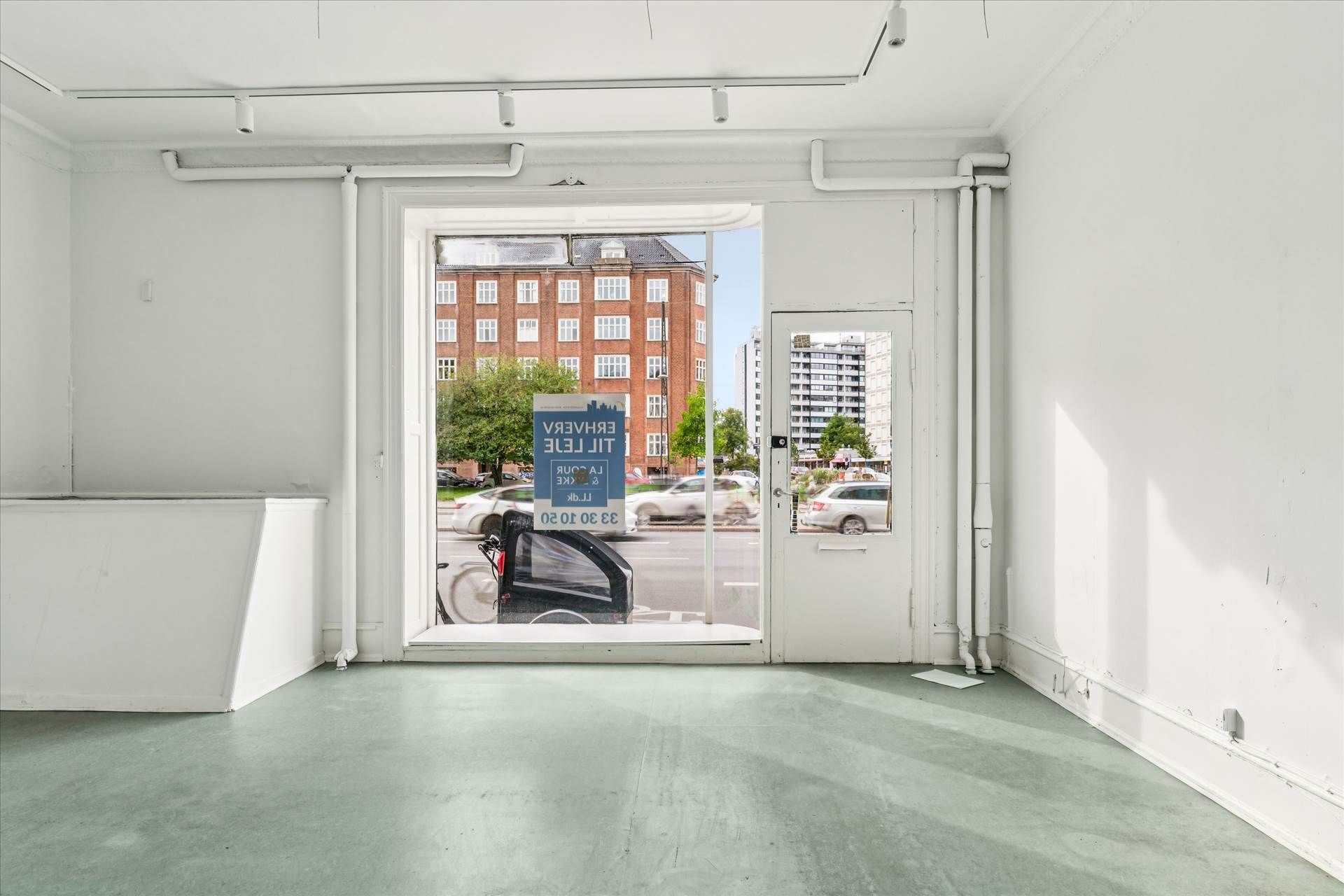 En åben glasdør med et skilt med teksten Charlottenlund Efterforsker 10.10.2023. På baggrunden er et hus og en bilparkering.