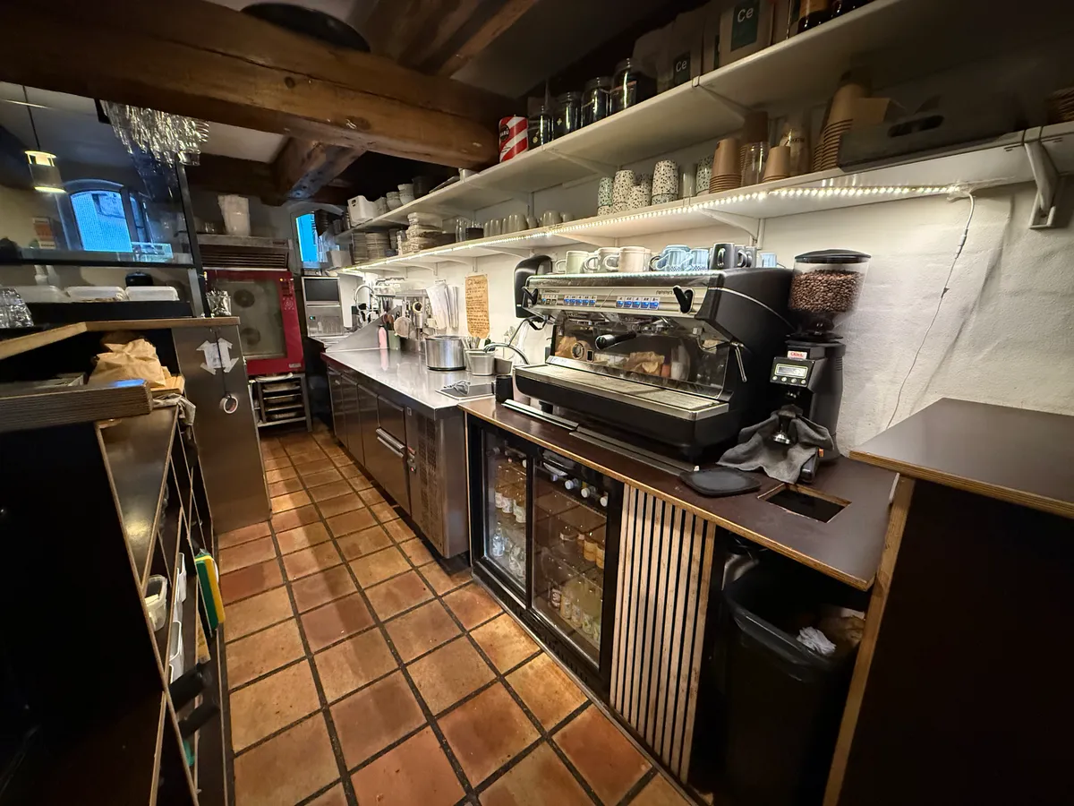 En køkken med en espressomaskine og en kaffemaskine og flere glas og flasker på et køkkenbord