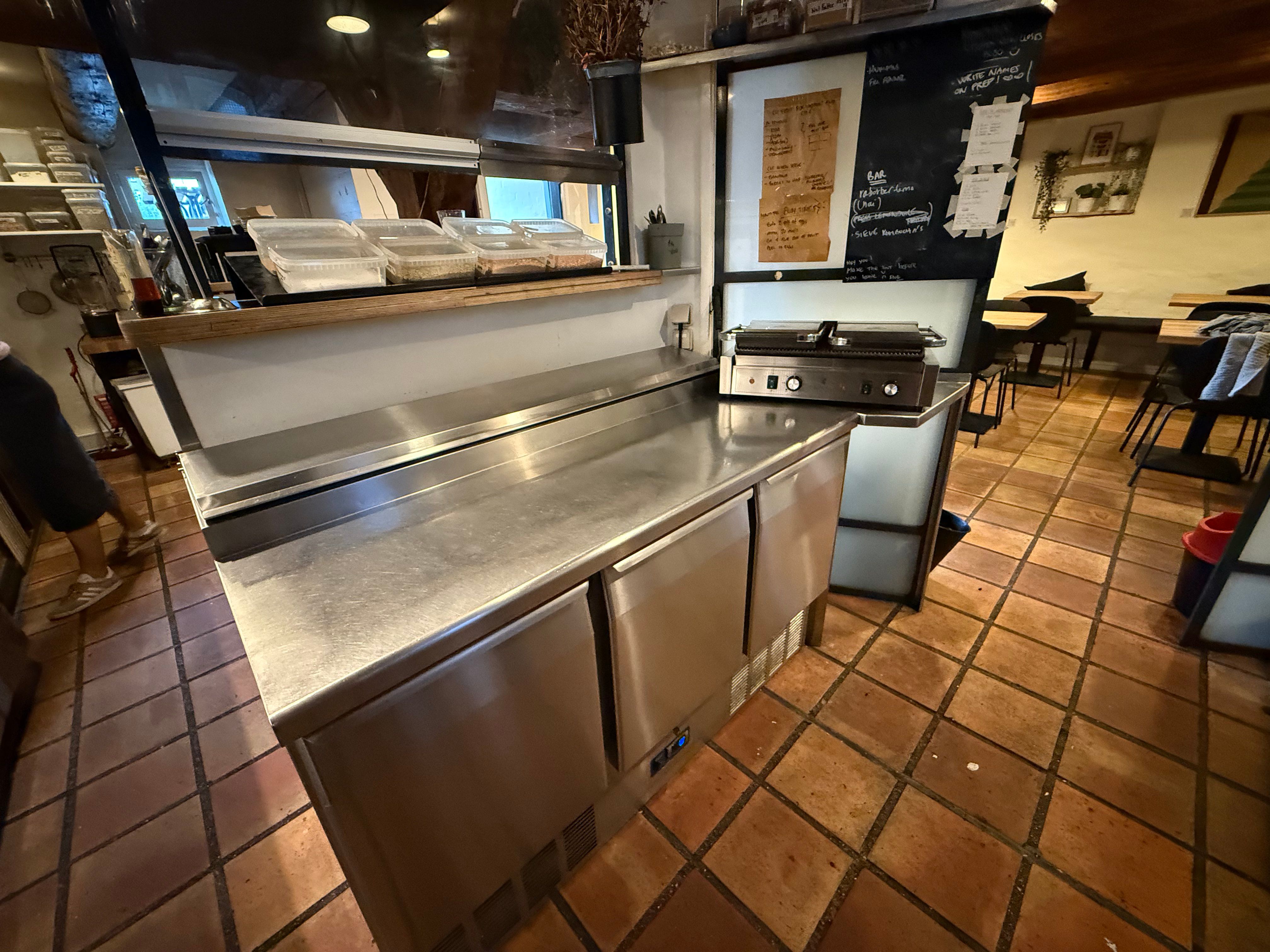 Køkken med rustfrit stål og udstyr som køleskabe og en grill, der er klar til brug