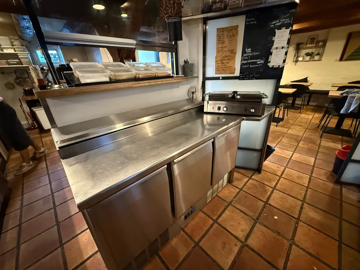 Køkken med rustfrit stål og udstyr som køleskabe og en grill, der er klar til brug