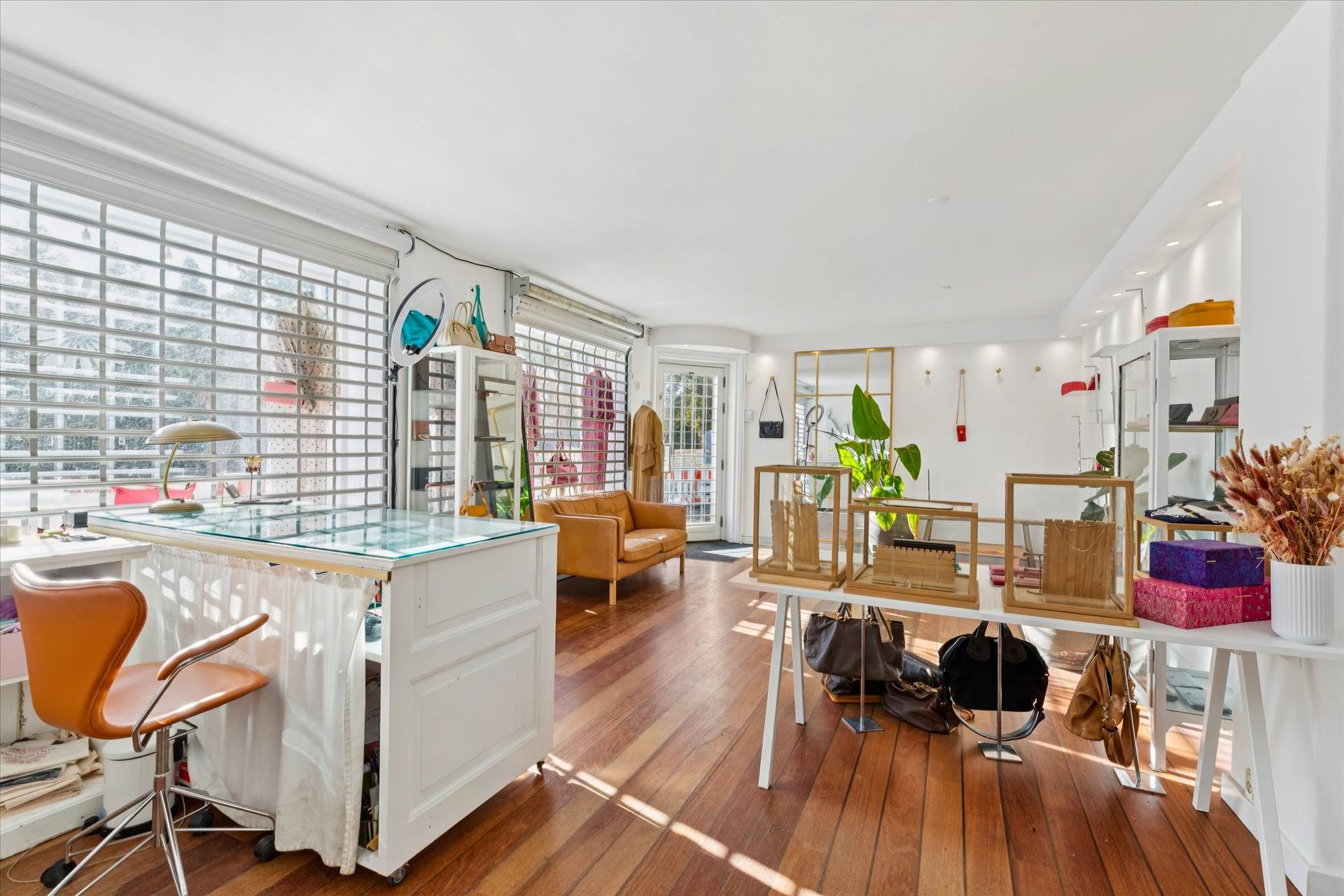 Indersiden af en butik med moderne møbler og prangende gulv. Væggene er hvide, og der er store vinduer med lysegardiner.