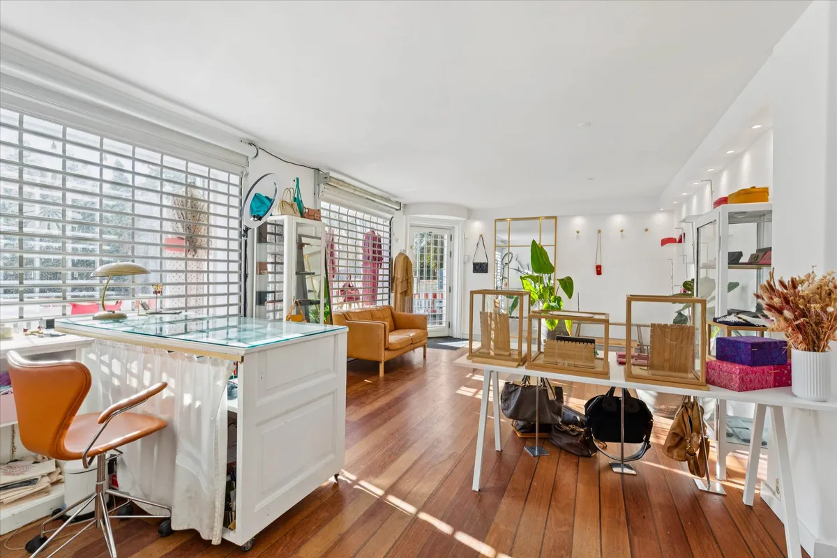 Indersiden af en butik med moderne møbler og prangende gulv. Væggene er hvide, og der er store vinduer med lysegardiner.