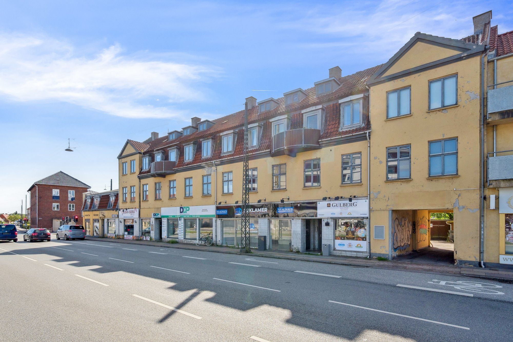 Langs Sallingvej 5 i Vanløse er der en række butikker med forskellige skilte, såsom Gulberg og DDP, samt en række biler