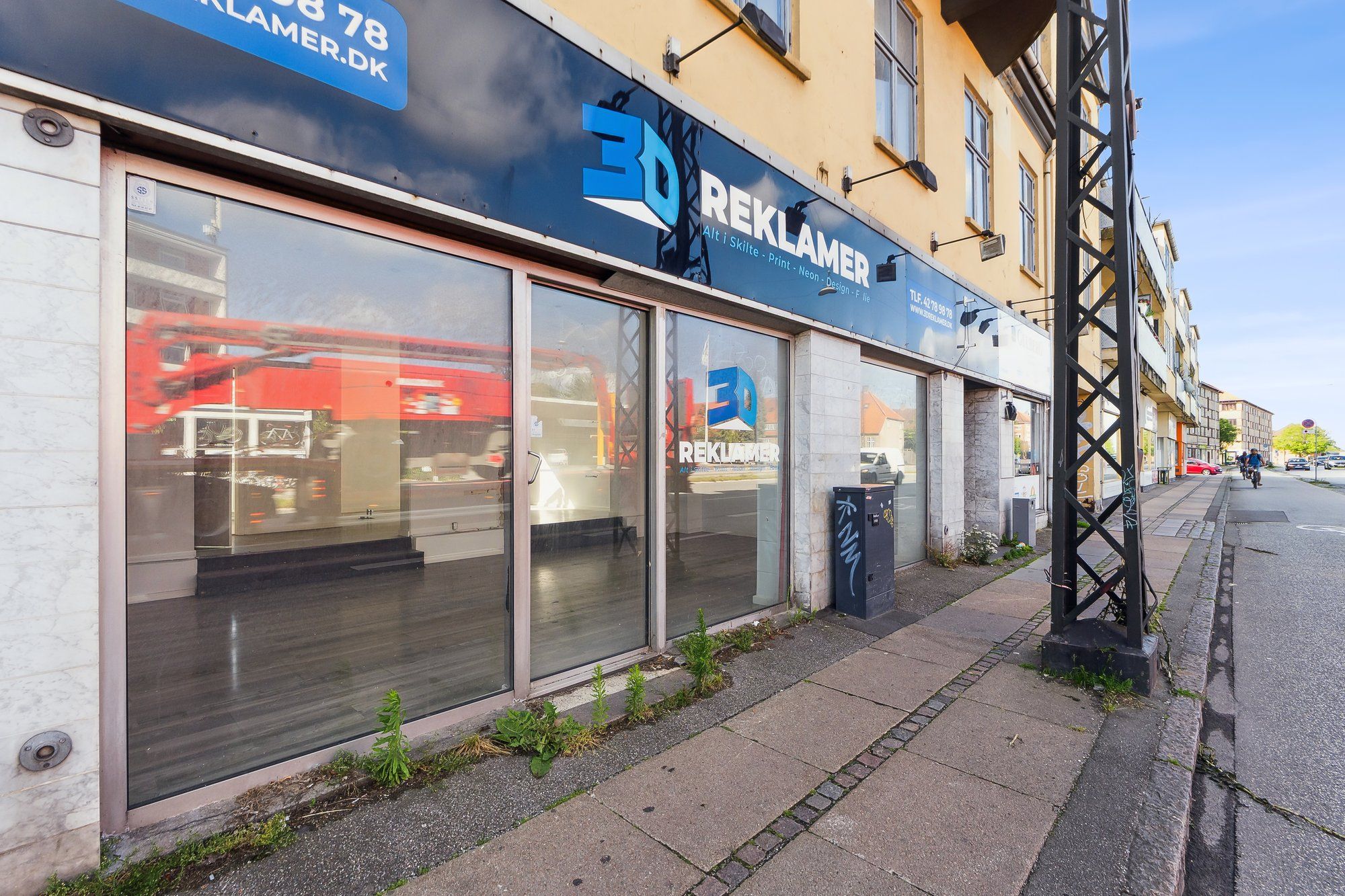 Butiksfront med logoet 3D Reklamer, der tilbyder skilte, print, neon, og design. Butikken har store glasvinduer, hvor