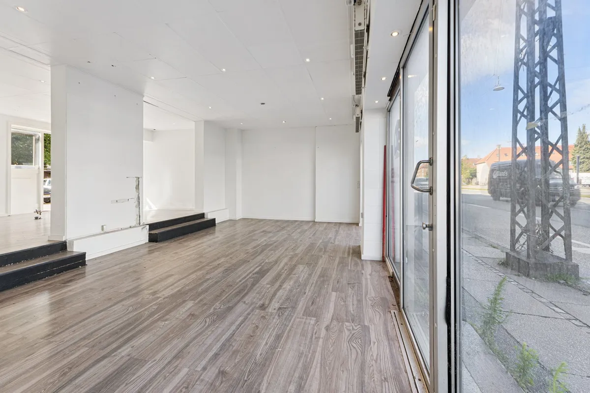 En stor glasdør i en stor, møbleret, tom stue med hårdt gulv og smukke hvide vægge og loft