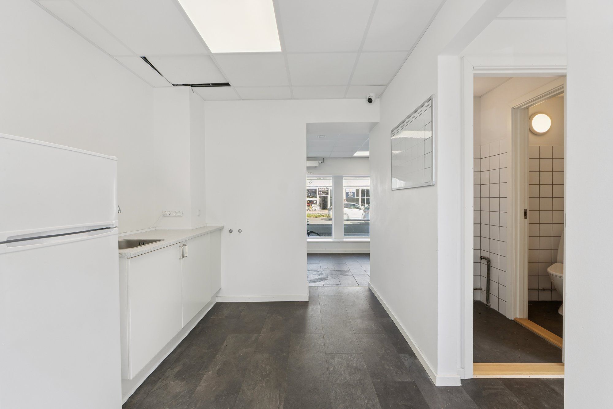 Lej en hvid og minimalistisk indrettet kontorplads med trægulv og moderne møbler. Pladsen er fuldt udstyret med køleskab,