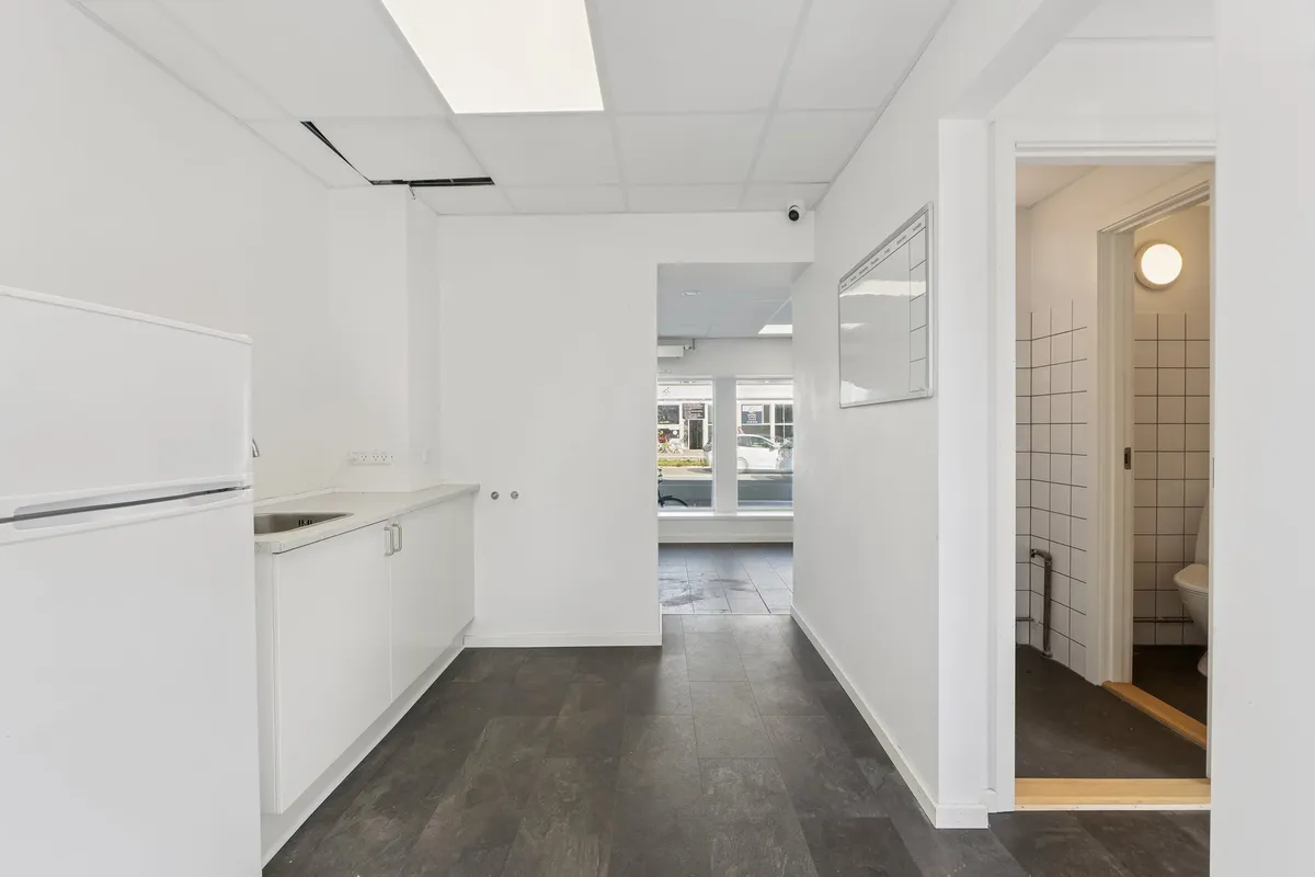 Lej en hvid og minimalistisk indrettet kontorplads med trægulv og moderne møbler. Pladsen er fuldt udstyret med køleskab,