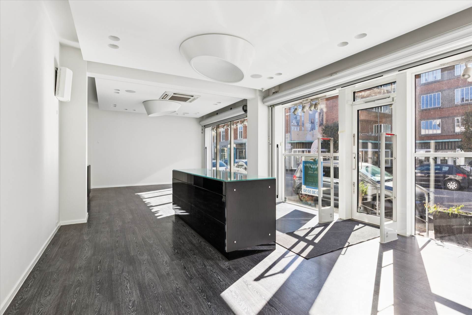 Et funktionelt og lyse butikslokale med en stor glasdør og moderne indretning, der gør det ideelt til detailforretning