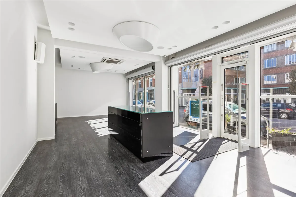 Et funktionelt og lyse butikslokale med en stor glasdør og moderne indretning, der gør det ideelt til detailforretning