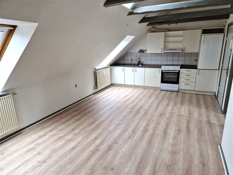 Foto af et tomt køkken med hvide vægge og loft og lysegul vinylgulv.