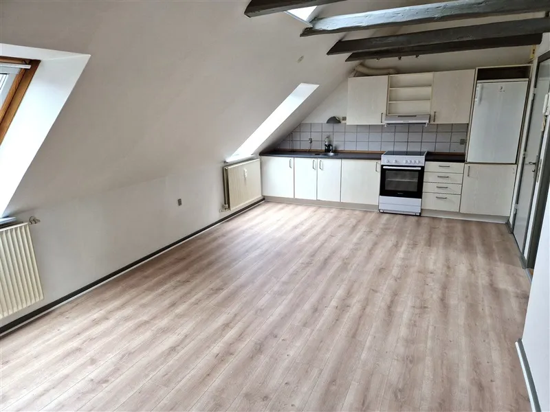 Foto af et tomt køkken med hvide vægge og loft og lysegul vinylgulv.