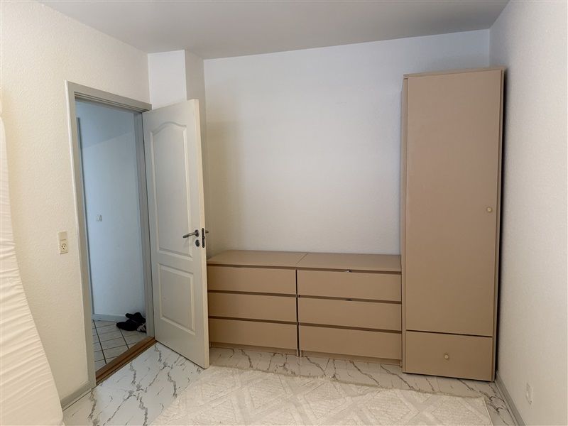 To rummelige og lyse værelser med hvide vægge og marmorgulv samt et rummelig skab med flere hylder og en række træskuffelader