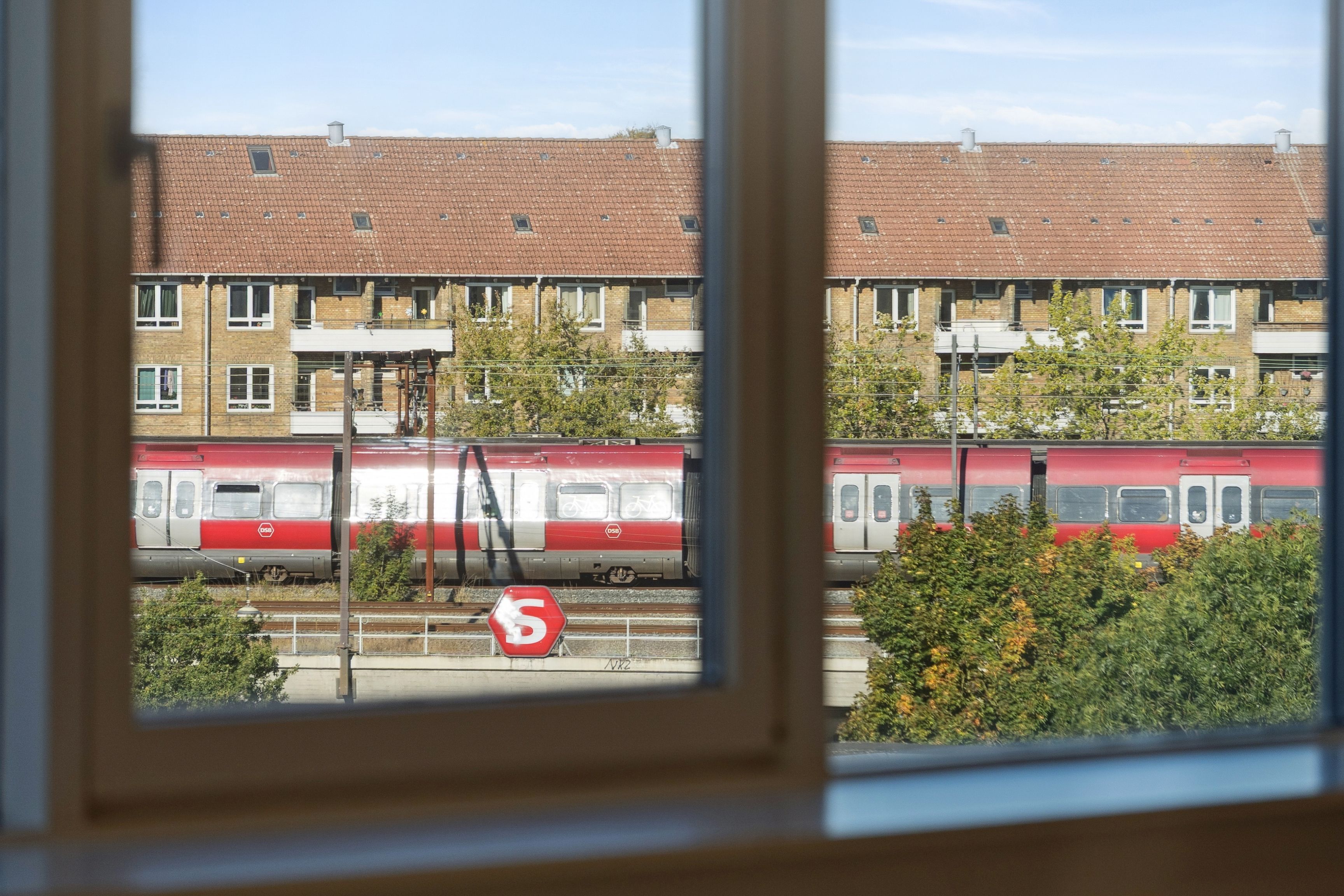 Træner er ude og træner i parken, mens en tog med rødt og hvidt design kører langs et togspor.