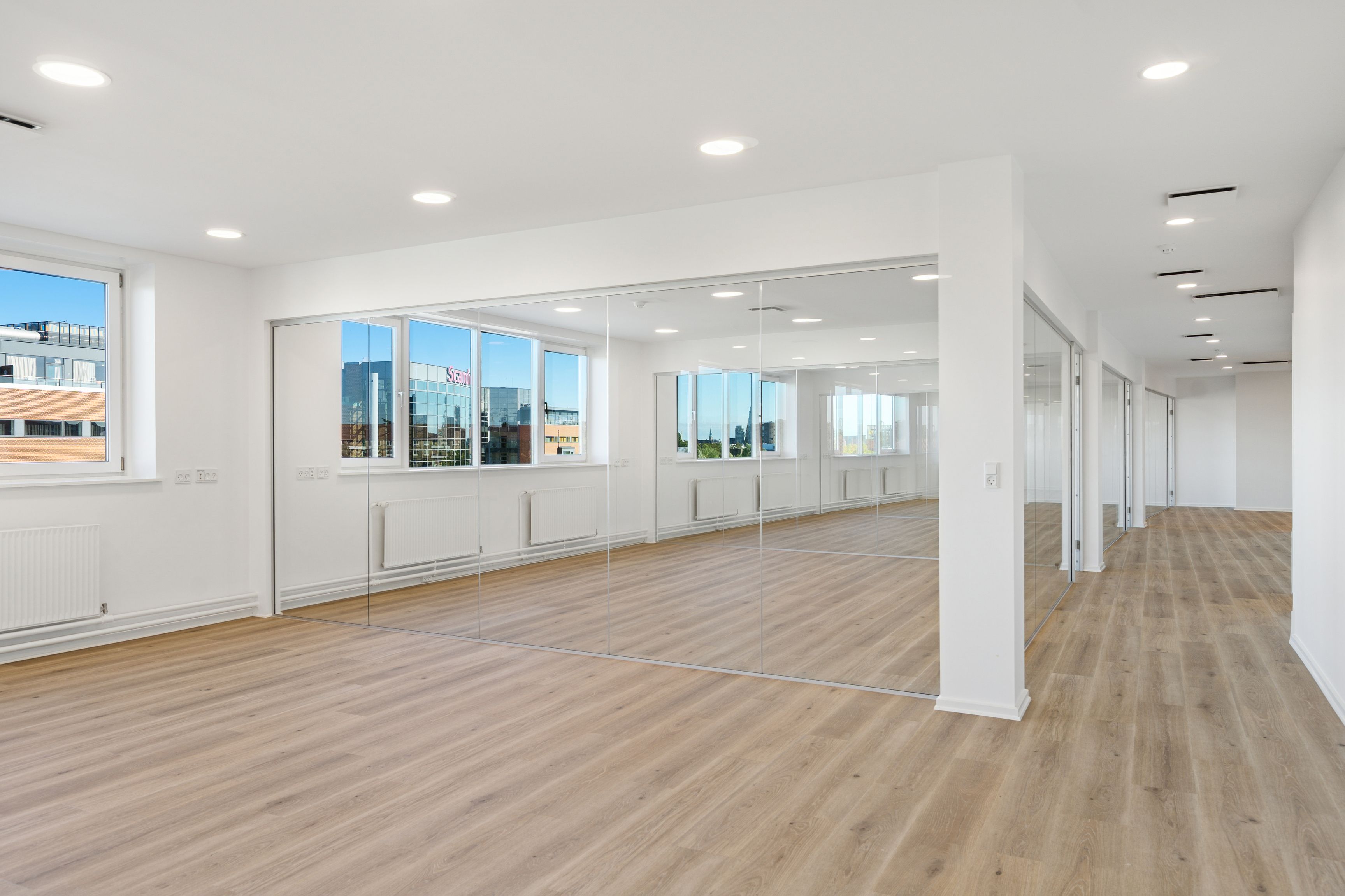 Lyst og rummeligt kontor med udsigt til byen og store vinduer. Store spejl og moderne design giver en følelse af rummelighed