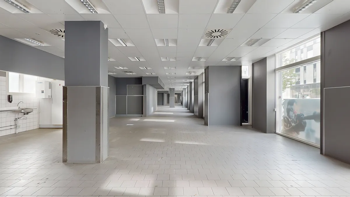 En tom gang med lysegult gulv og hvide vægge og loft. Det er en delvist tom og moderne indretning.