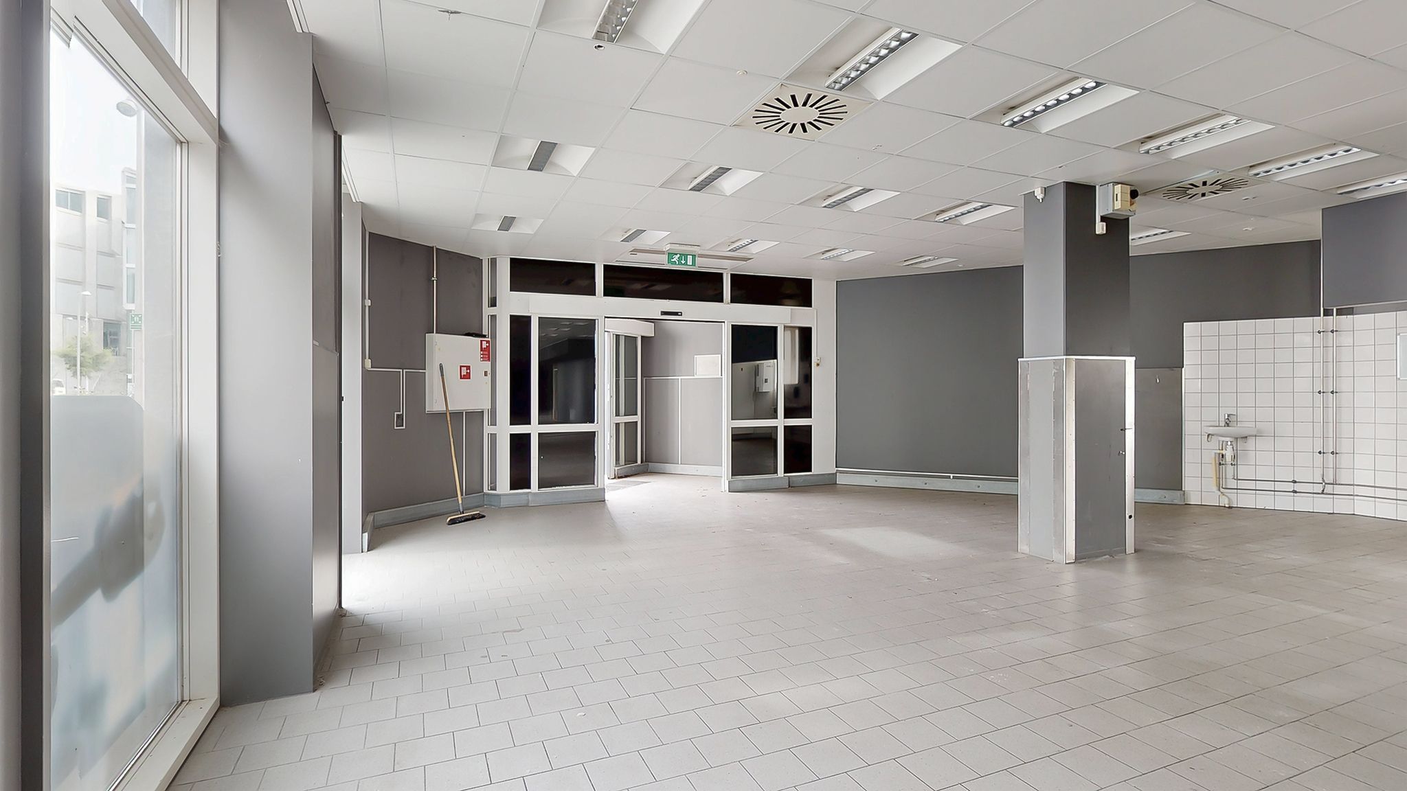 Stor tom lejlighed med hvide fliser og glasruder og en indgangsdør med et udgangsskilt