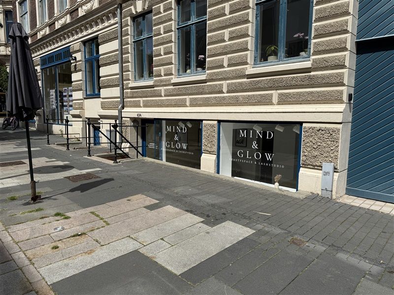 En gård med lejemålet Mind & Glow på en sidegade i Fredericia. Lejemålet har store vinduer og en åben indgang.