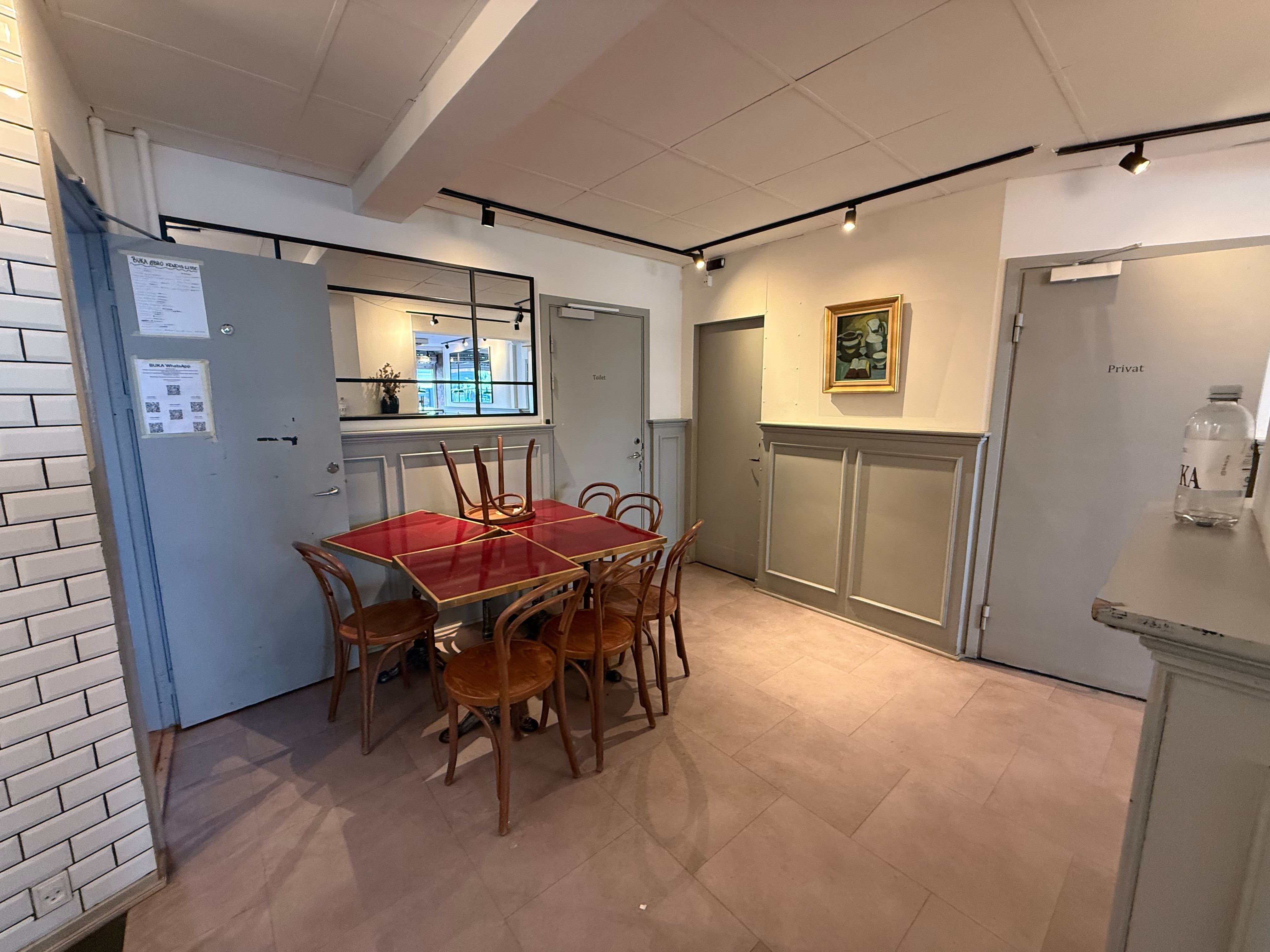 Møbler er samlet i et moderne, rummeligt lokale med et bord og stole, lysekroner og en vægmaleri