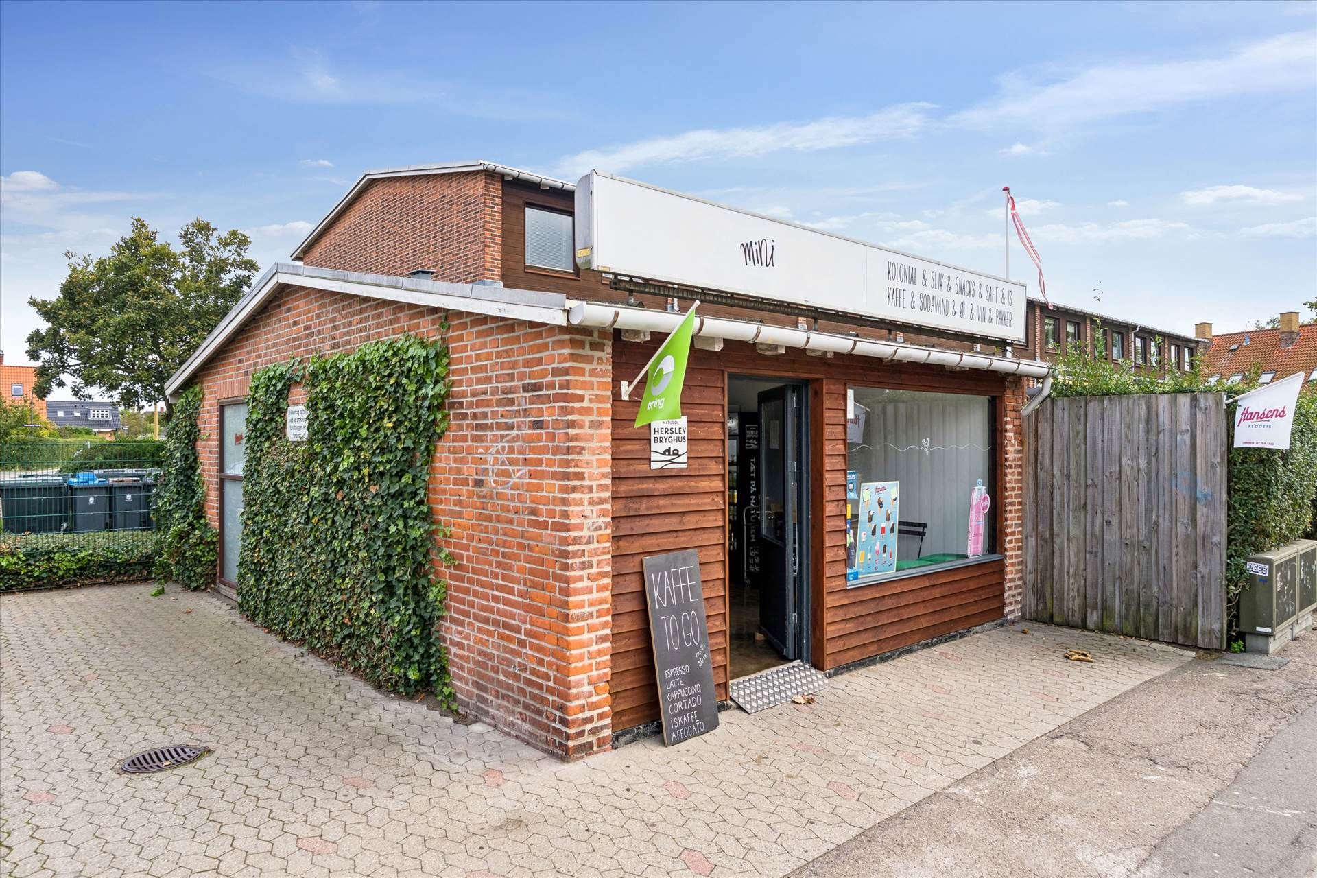 Mini kiosk med udsalg af kaffe og små madvarer placeret i bydelen. Et skilt med teksten Mini og flere skriftlige reklamer