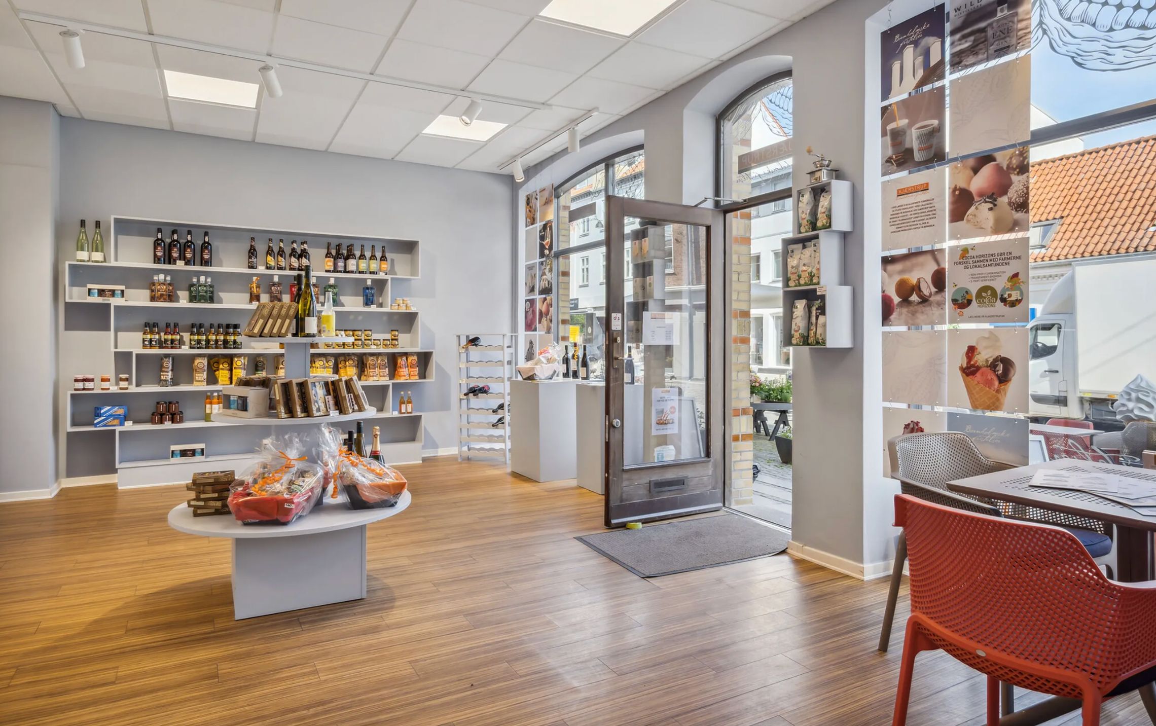 En møbleret restaurant med et gulv af træ og flere hylder med varer og vinflasker